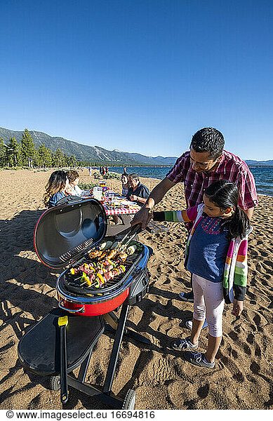 A family enjoys a beach BBQ on the shoreline of Lake Tahoe  NV