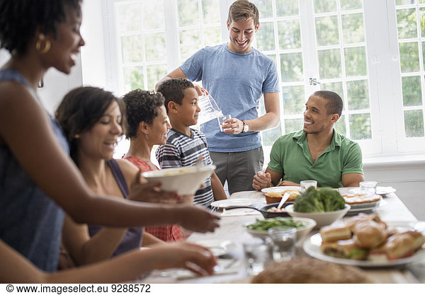 A family gathering  men  women and children around a dining table sharing a meal.
