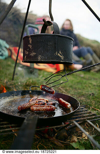 A family grills sausages and boils water on a camp fire near Ellingstring  North Yorkshire  England  UK  on March 22 2009.