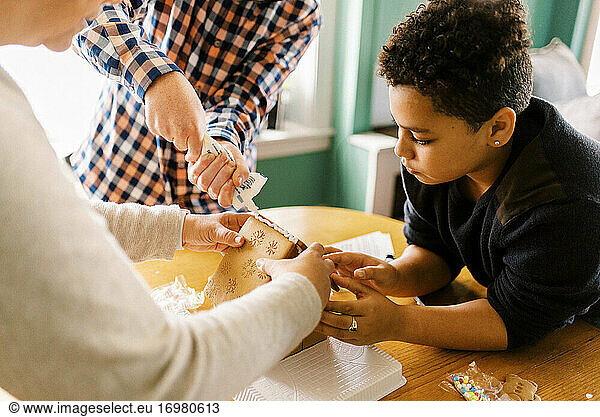 A family making a gingerbread house together in the living room