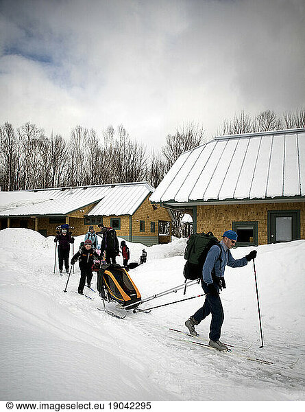 A family of cross country skiers leaving the Flagstaff Hut of Maine Huts and Trails. Maine  New England.