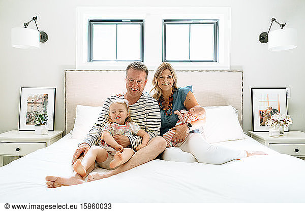 A family of four sitting together in a modern bedroom