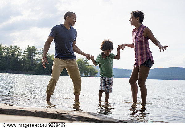 A family  parents and son spending time together by a lake in summer.