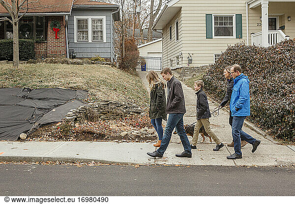 A family walk together with dog through suburban neighborhood
