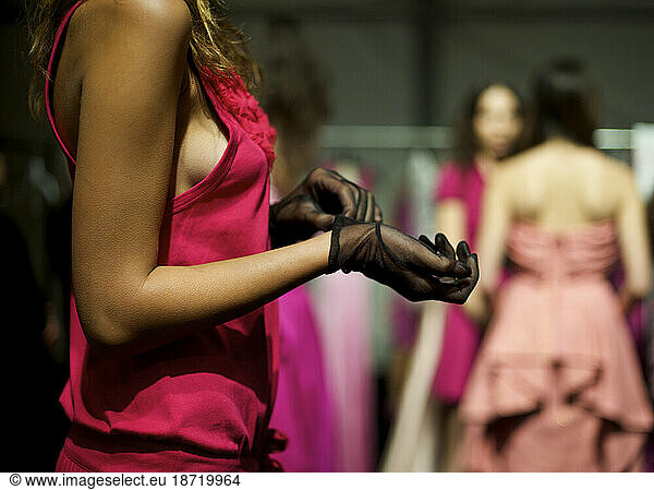 A fashion model puts on a glove while waiting backstage during Fashion Week L.A.