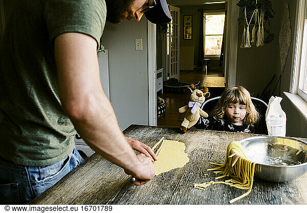 A father and daughter bonding over making pasta at home