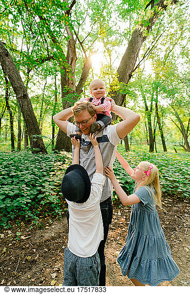 A father and his three kids playing together in the forest