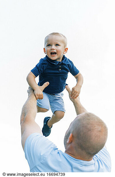 A father throwing his son into the air during playtime outside