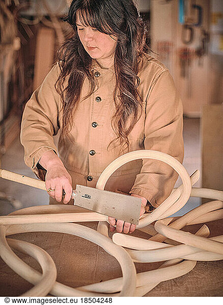 A female artist in her studio works with one of her wood sculptures