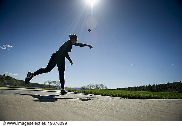 A female athlete throws a shot-put during track practice.