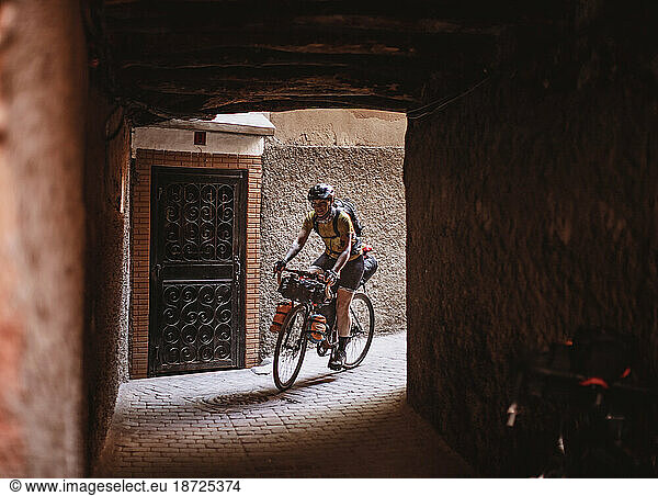 A female cyclist rides through a tunnel in the medina  Marrakesh