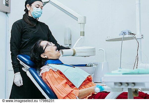 A female dentist performing dental x-rays  Female dentist performing x-rays on a patient  Female dentist performing dental x-rays