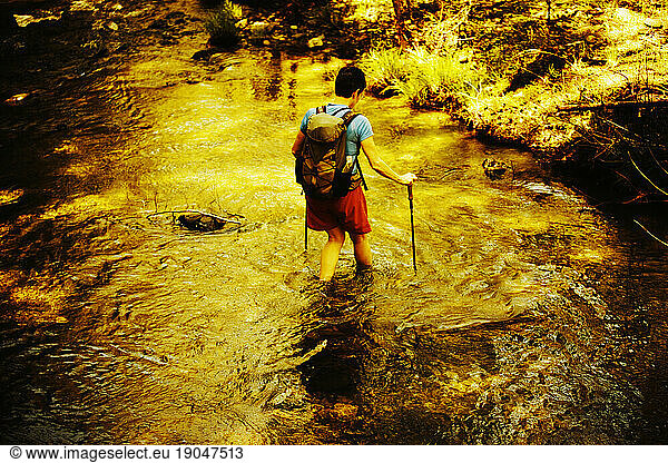 A female hiker crossing a creek.