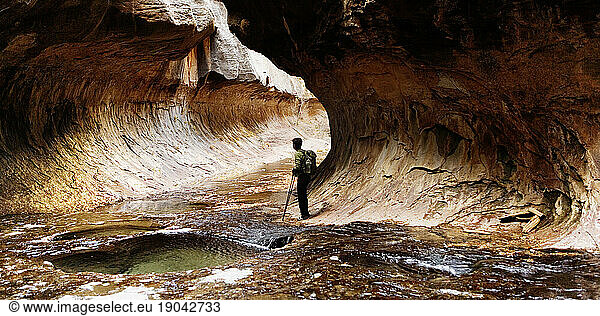 A female hiker stands in The Subway which is known for its lower tunnel-like passage. Zion National Park  Utah.