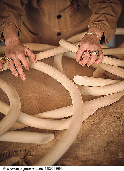 A female sculptor adjusts pieces of a wooden artwork in her studio