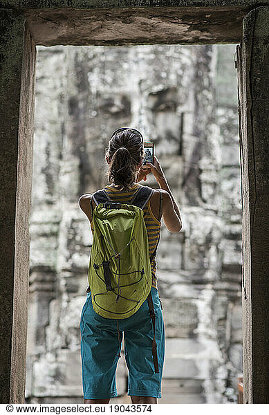 A female tourist taking pictures at Bayon  ankor Thom temple  Angkor Wat  Siem Reap  Cambodia.