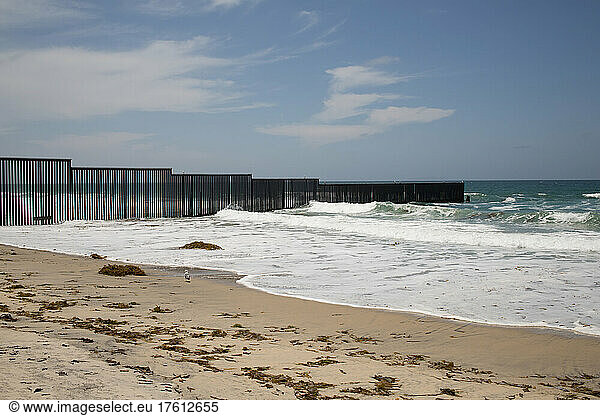 A fence marks the United States/Mexico border where it meets the Pacific Ocean.