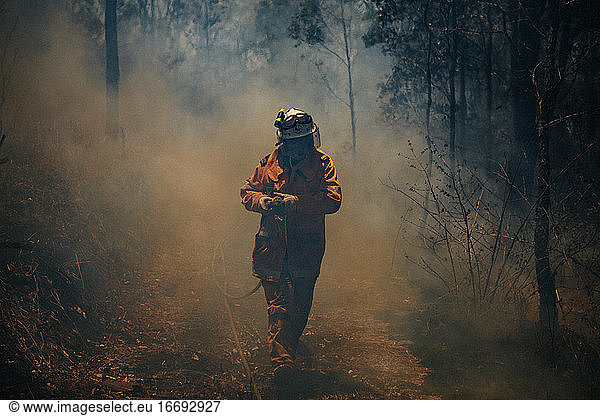 A firefighter with a hose during a large wildfire in Austalia