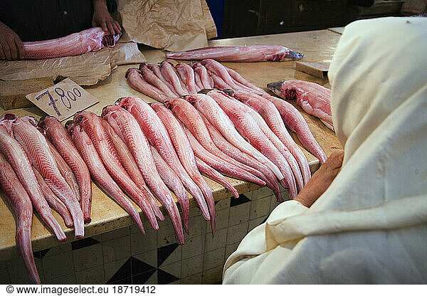 A fishmonger selling fish to a Muslim woman wearing white Hijab.
