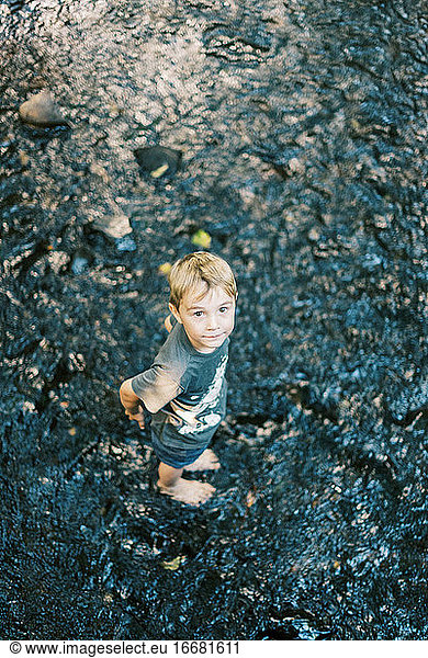 A five year old boy getting his feet wet in a river