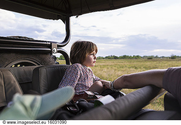 A five year old boy on safari  in a jeep in a game reserve
