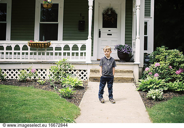 A five year old posing for a portrait in front of his door