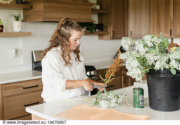 A florist cutting flowers to arrange in a cut flower bouquet in