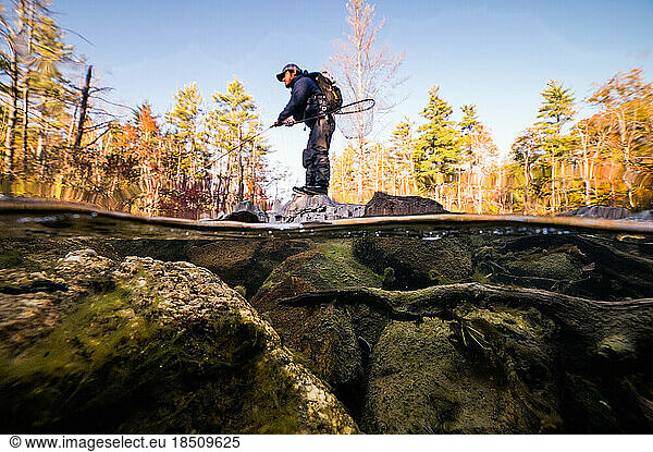 A fly-fisherman fishing with streamers on a river in fall
