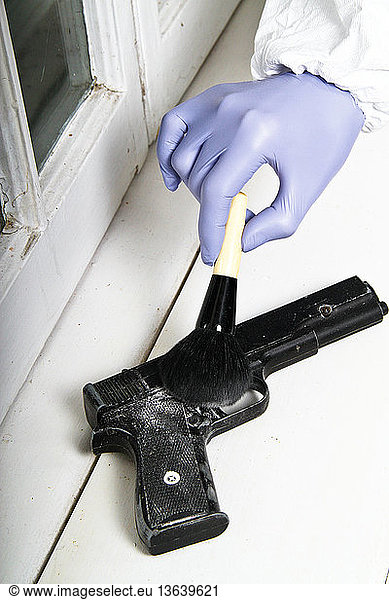 A forensic investigator dusting a gun for fingerprints at a crime scene.