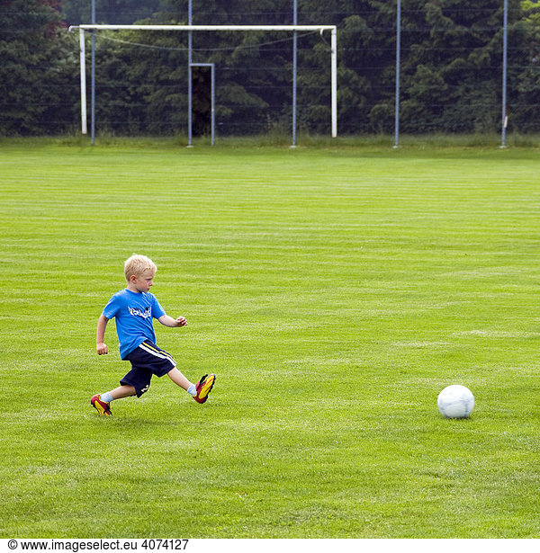 A four-year-old boy is training at a soccer ground