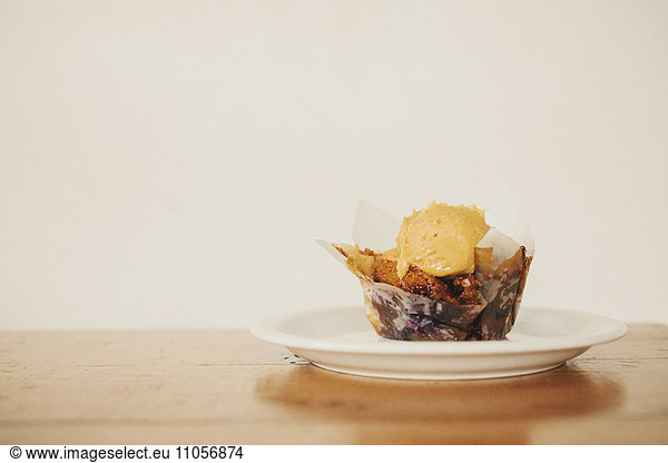 A fresh baked muffin with ice cream on a plate.
