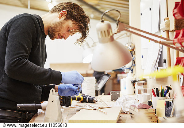 A furniture workshop making bespoke contemporary furniture pieces using traditional skills in modern design. A man standing at a workbench.