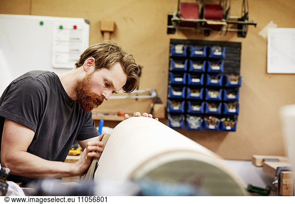 A furniture workshop making bespoke contemporary furniture pieces using traditional skills in modern design. A man working on a curved wooden piece.