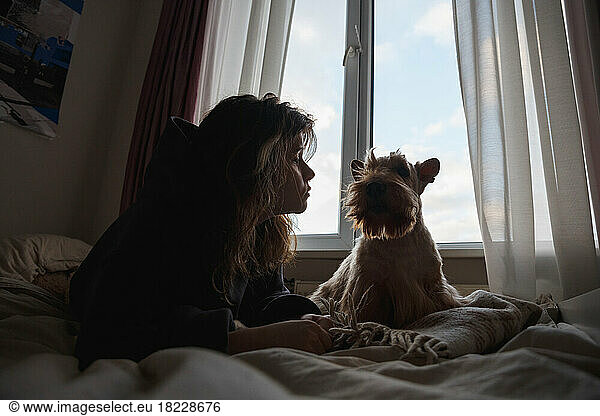 A girl and a funny dog in front of the window.