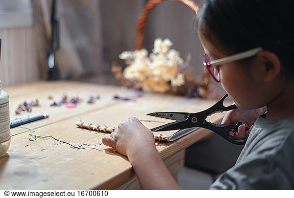 A girl cutting a rope on her hand craft work