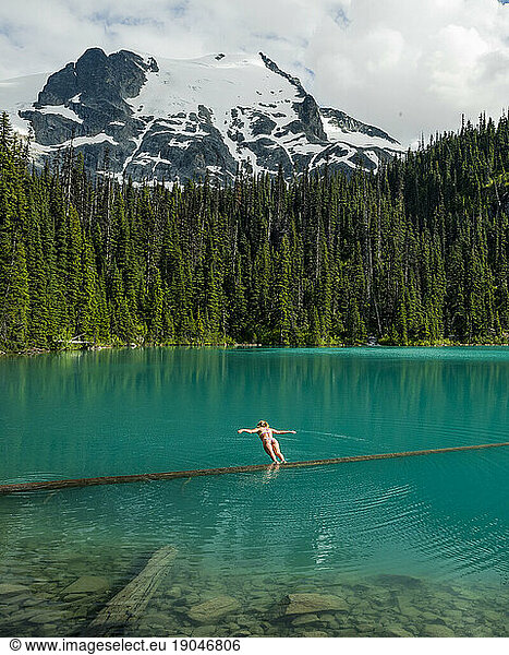 A girl does a belly flop into the vibrant blue Joffre Lakes.