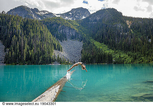 A girl does perfect back dive into the blue waters of Joffre Lakes