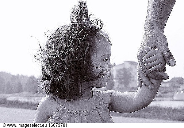 a girl holds her father's hand against the background of the city