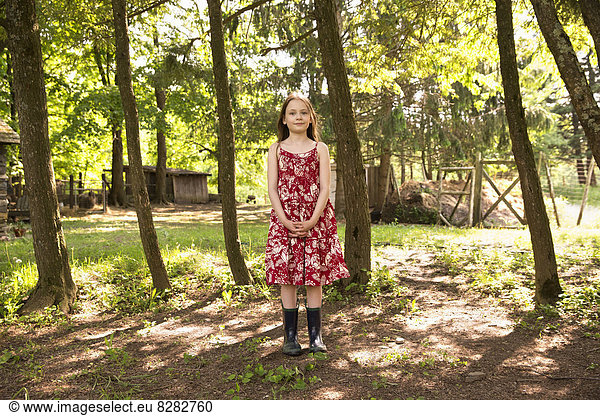 A Girl In A Summer Dress Standing In A Grove Of Trees.