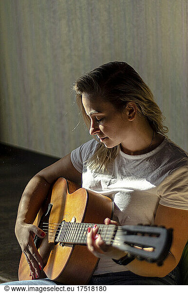 a girl in a white t-shirt plays the guitar