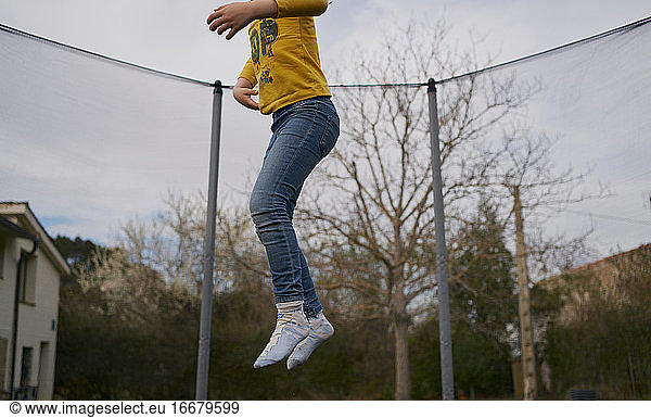 A girl in casual clothes jumping on a trampoline