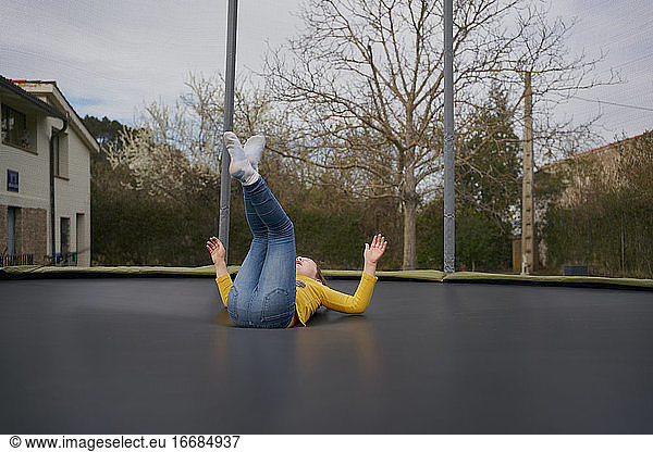 A girl in casual clothes jumping on a trampoline