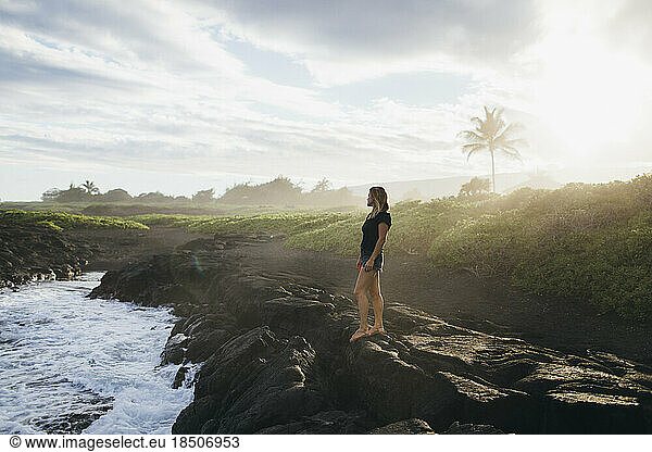 A girl is walking on lava rocks near the ocean  Big Island  Hawaii.