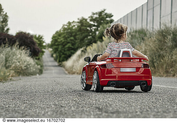 A girl riding a toy car
