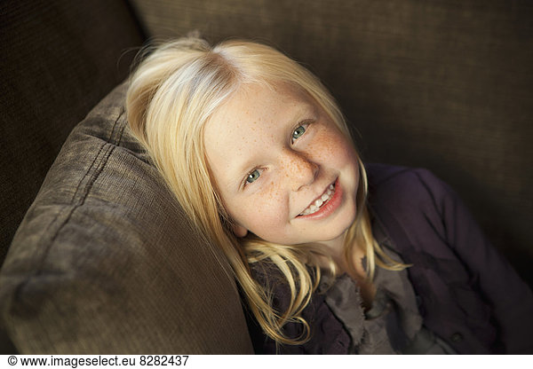 A Girl Sitting On A Couch  Smiling At The Camera.