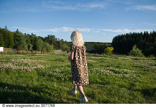 A girl walking away on a field Sweden.