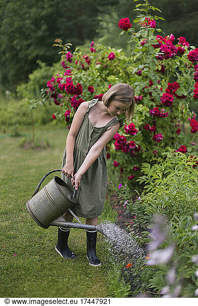 A girl watering flowers in the garden. Work in the garden.