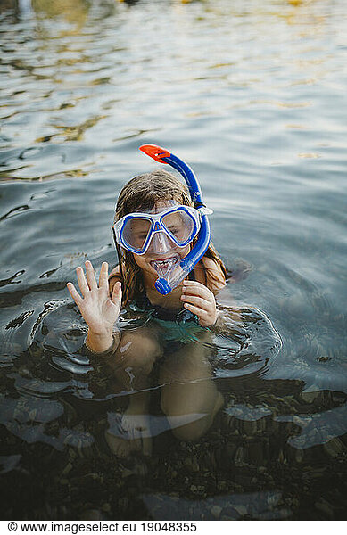 A girl wearing snorkel waving goodbye before diving into the red sea