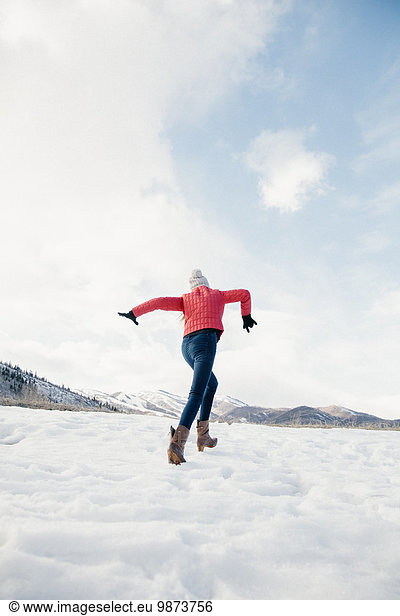 A girl with long legs running across the snow.