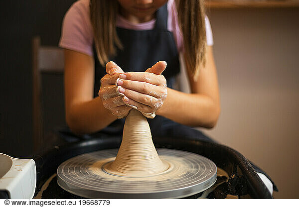 A girl working with clay on a Potter's wheel close up. Tradition